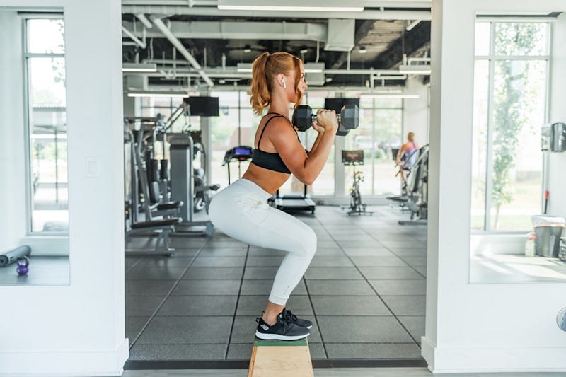 Individual performing a squat with dumbbells