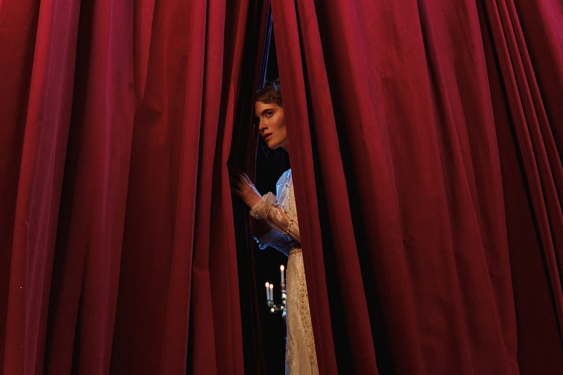 A performer poised behind a curtain.